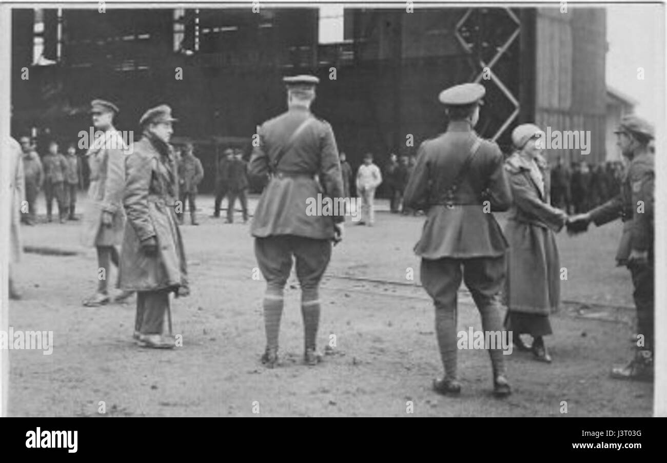 Cette photographie historique montre le roi Albert Ier de Belgique et la reine Elisabeth sur un aérodrome, probablement lors d'une visite officielle. L'image capture un moment important de l'engagement royal avec l'histoire de l'aviation. Banque D'Images
