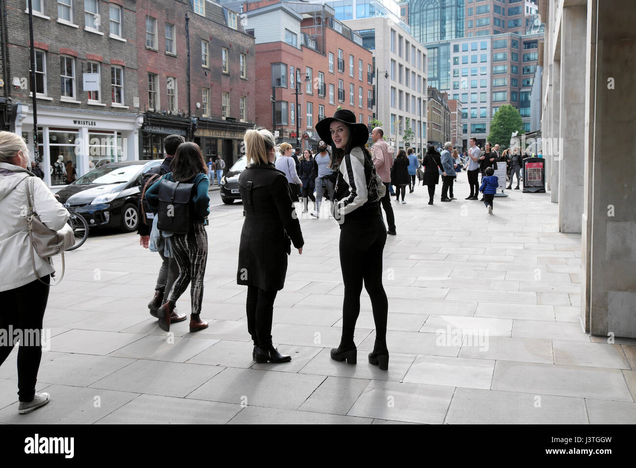 Attractive young woman wearing black hat smiling standing avec ami sur Brushfield Street près de Marché de Spitalfields dans East London E1 KATHY DEWITT Banque D'Images