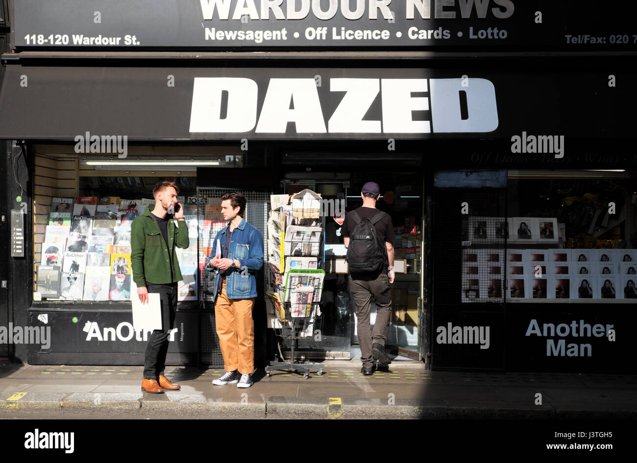 L'homme et ami talking on mobile phone en dehors de Wardour News presse boutique avec DAZED magazine sign in Wardour Street Soho Londres W1F UK KATHY DEWITT Banque D'Images