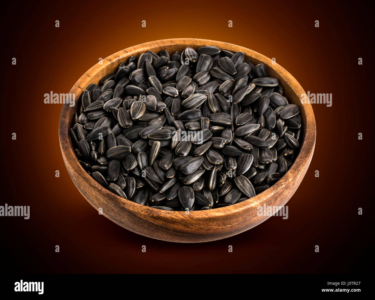 Les graines de tournesol noires dans bol en bois isolé Banque D'Images