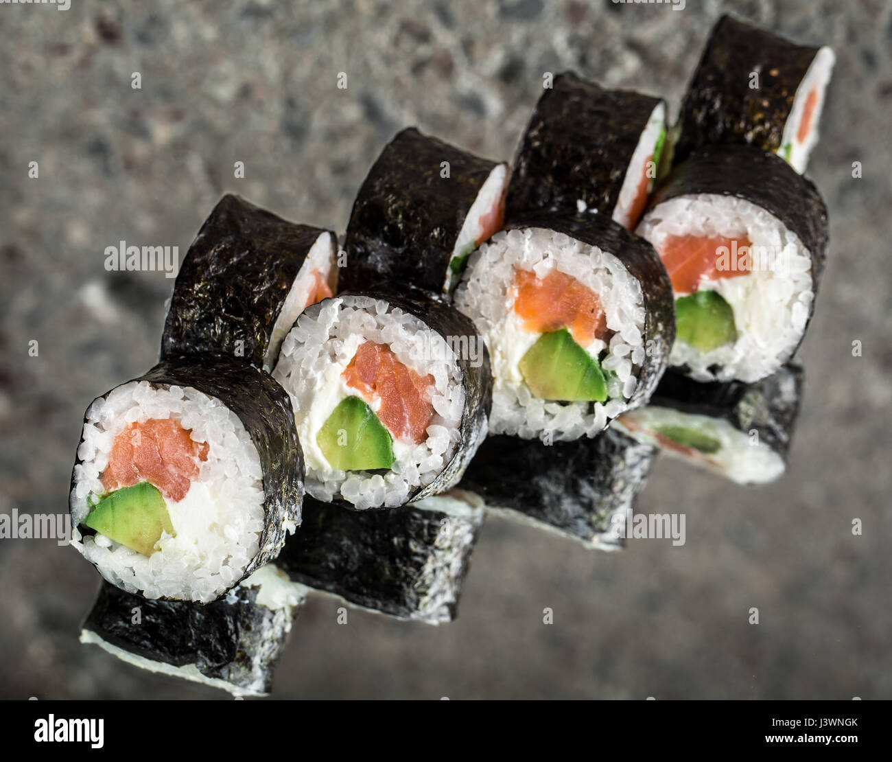 Sushi roll avec le saumon, le fromage à la crème et de l'avocat sur l'arrière-plan cocnrete Banque D'Images