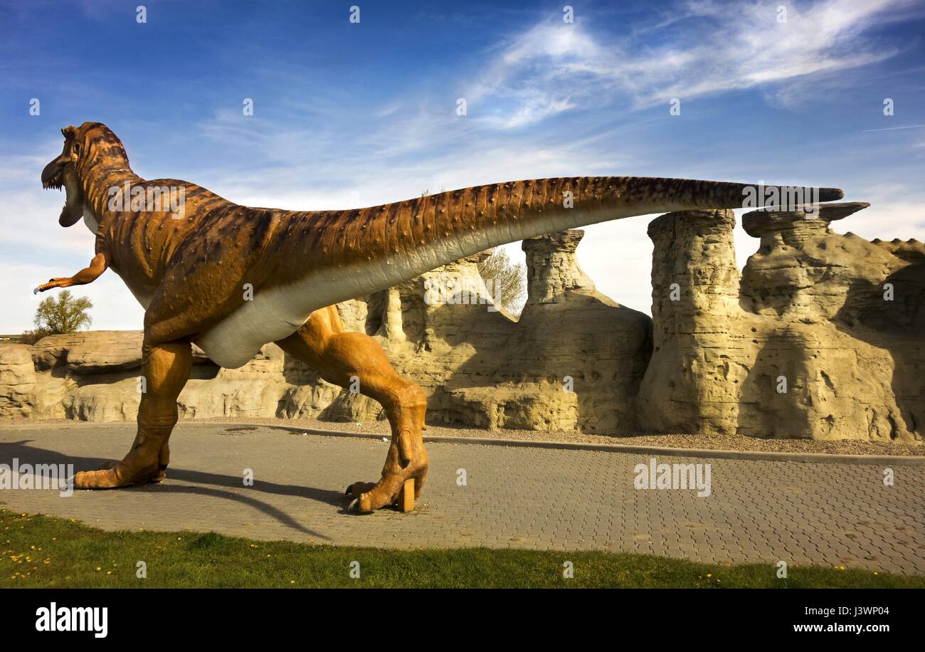 Massive Dinosaur animal figure modèle Statue Walking by Hoodoo Rock formations. Centre d'accueil touristique des parcs de l'Alberta du Sud à Milk River, Canada Banque D'Images