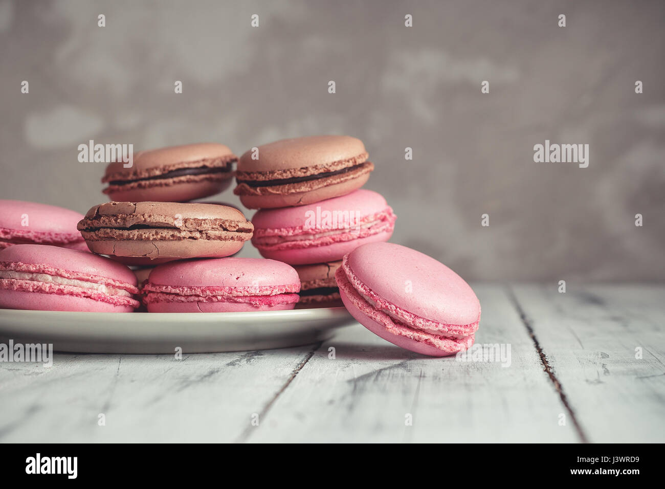 Pile de framboise et macarons au chocolat macarons aux couleurs pastel ou sur fond noir en béton Banque D'Images