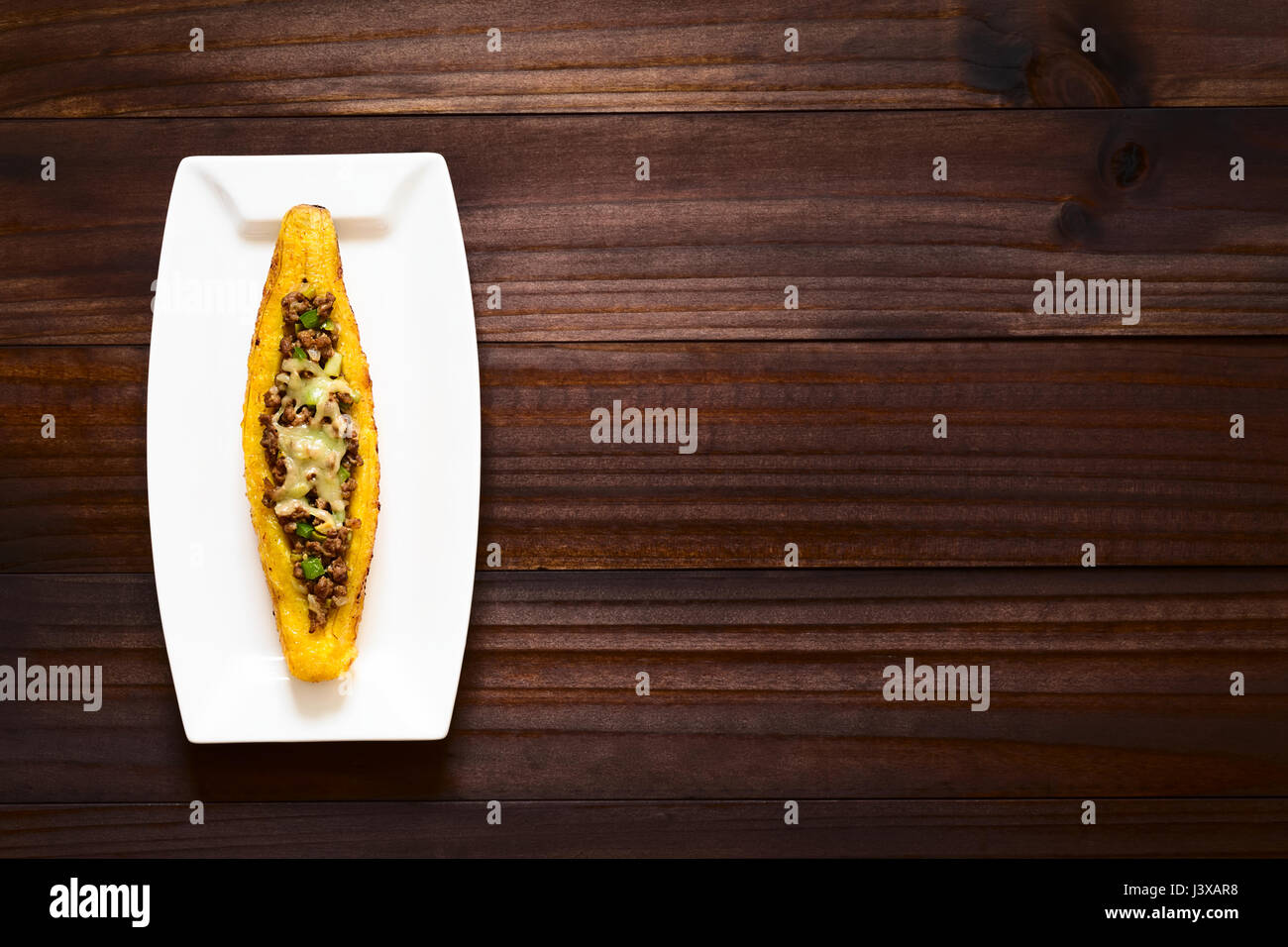 Plantain mûres cuites au four farcies de viande hachée, d'olive, poivron vert et l'oignon, parsemées de fromage, un plat traditionnel en Amérique centrale Banque D'Images