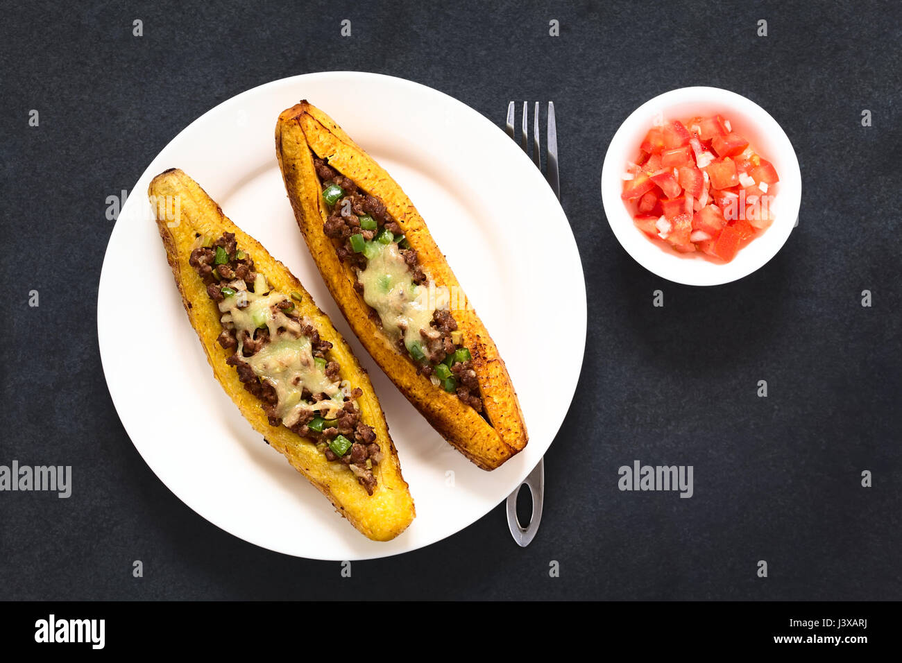 Plantain mûres cuites au four farcies de viande hachée, d'olive, poivron vert et l'oignon, parsemées de fromage, un plat traditionnel en Amérique centrale Banque D'Images