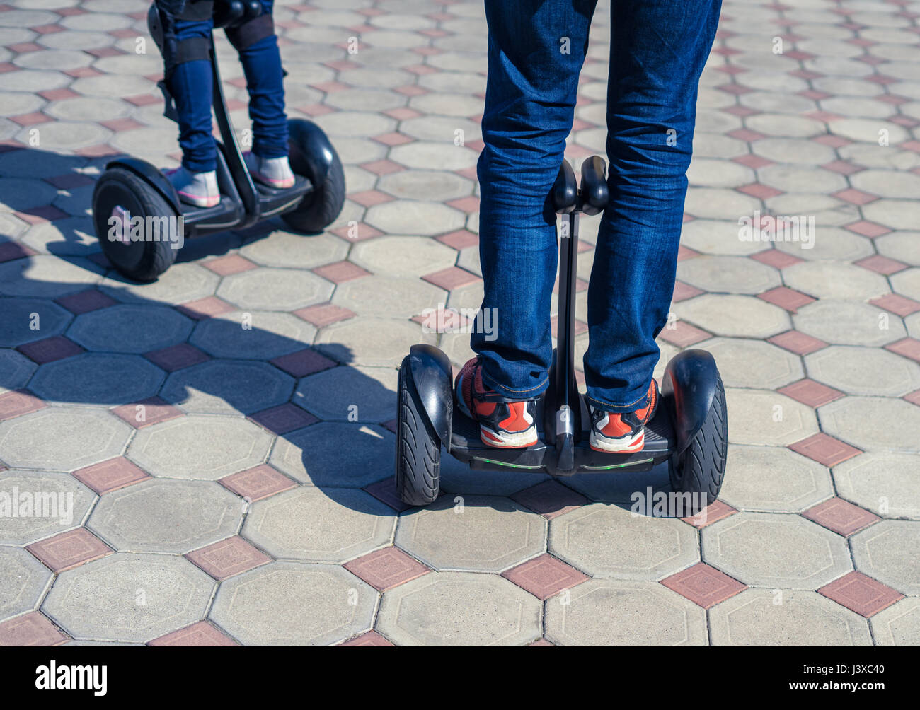 Jeune père et fille équitation mini électrique en hoverboard park Banque D'Images