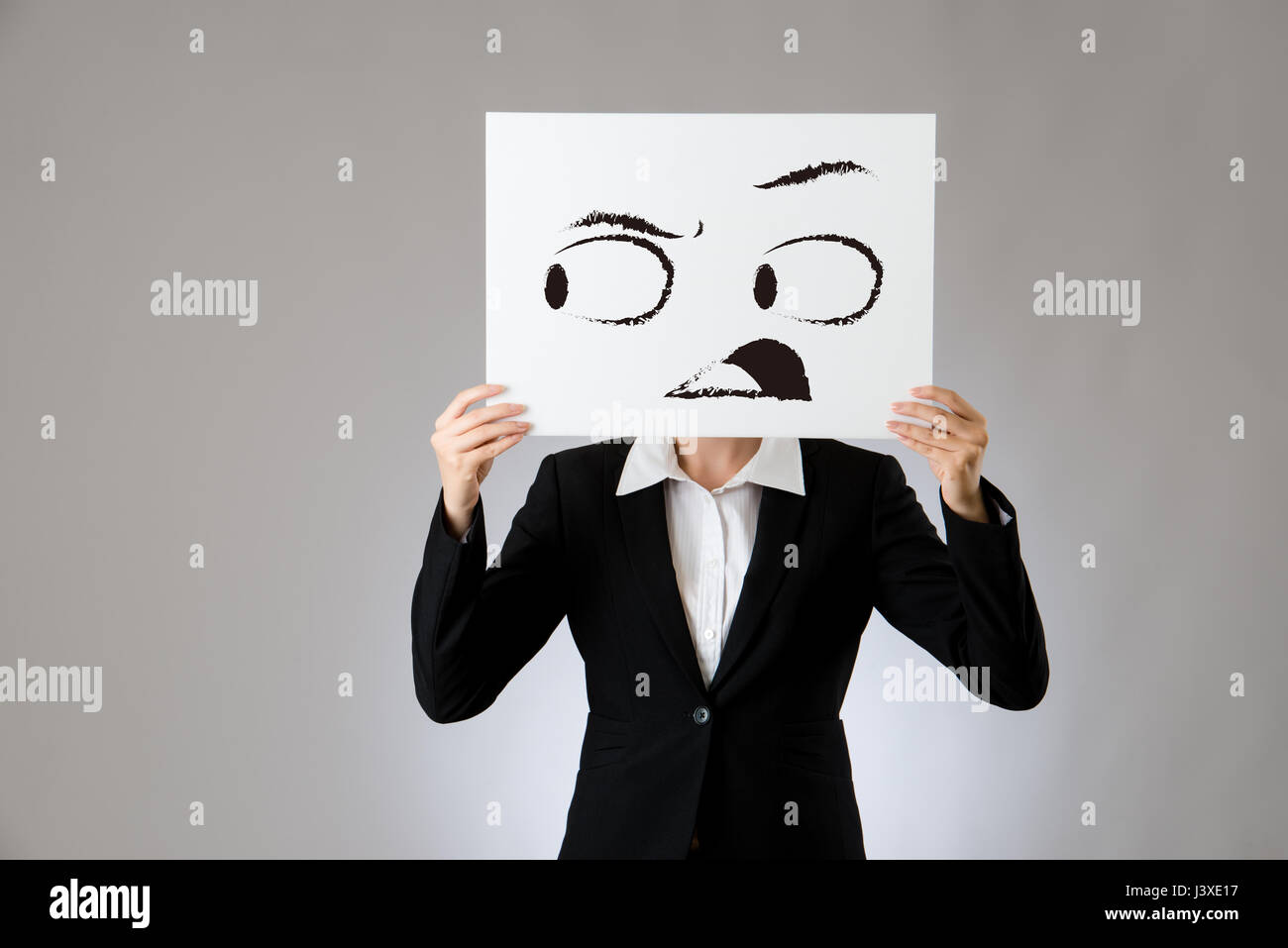 L'expression choquée face dessin sur carte blanche vide tenue par une femme d'affaires. isolé sur fond gris. business office entreprise concept. Banque D'Images