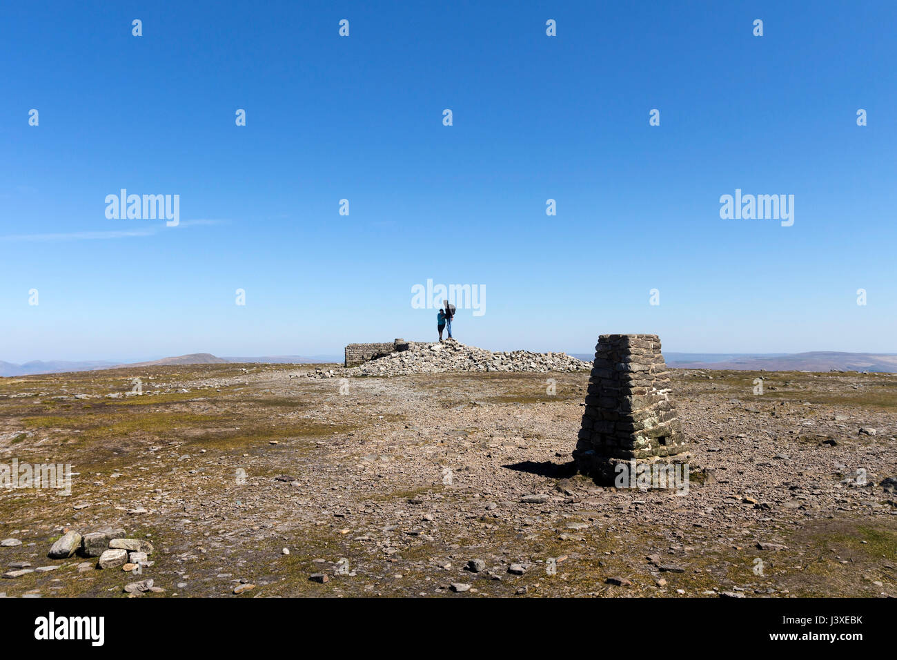 Les marcheurs se tenant debout sur le sommet d'Ingleborough sous un ciel bleu, du Yorkshire, UK Banque D'Images