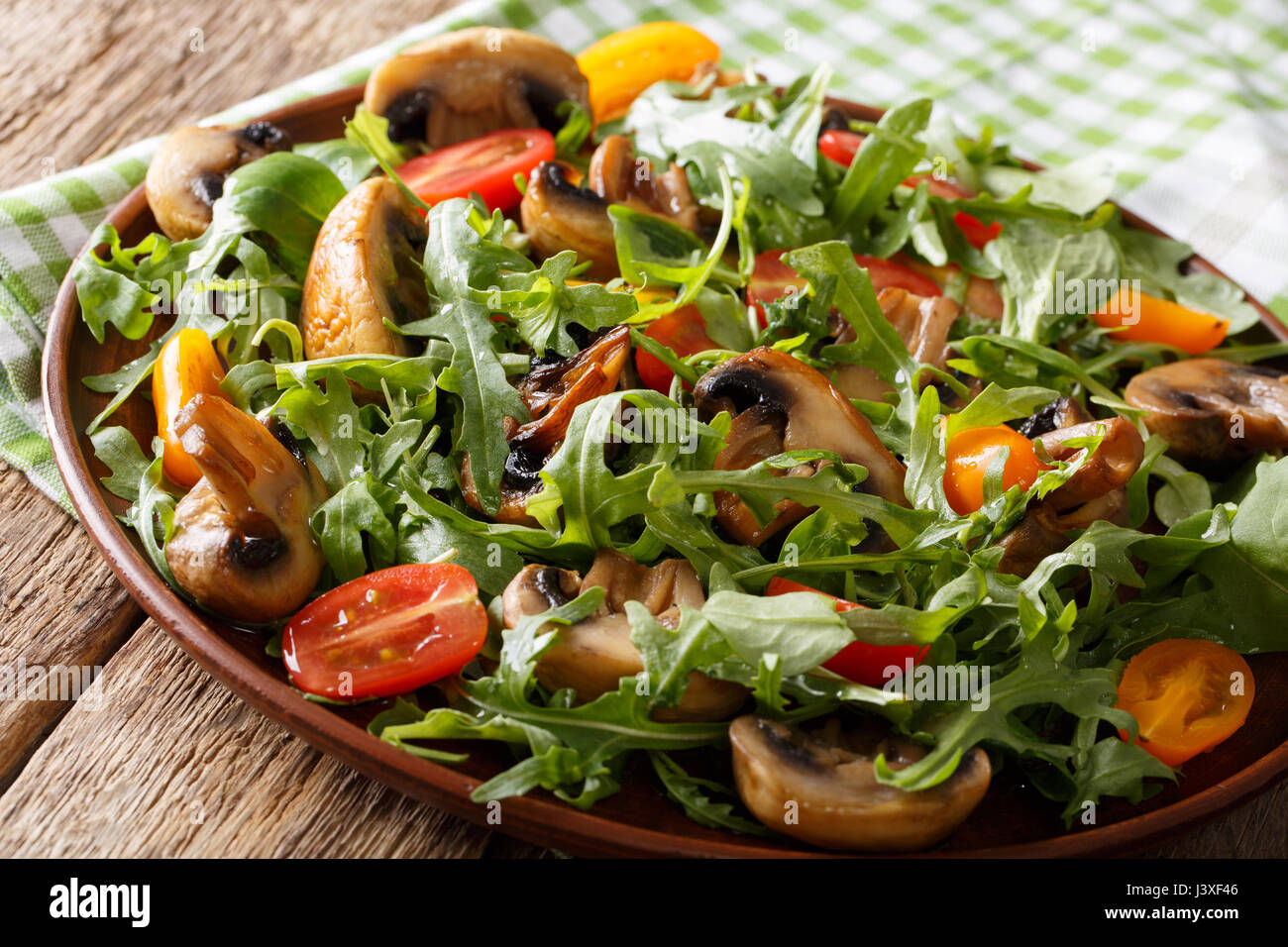 Végétalien : salade de champignons poêlés, roquette, tomates cerises close-up sur une plaque horizontale. Banque D'Images