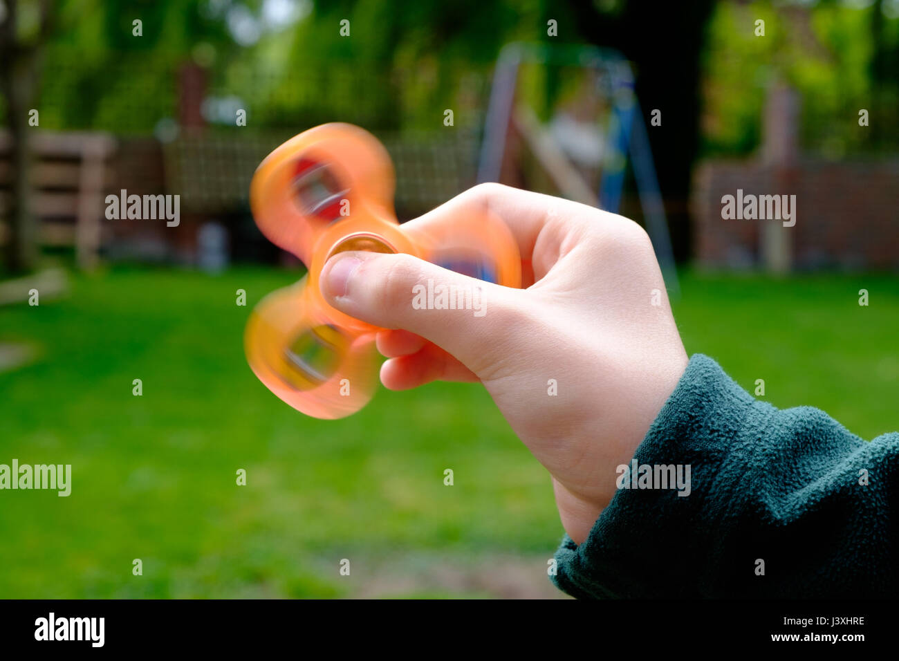 Jeune garçon tenant une orange fidget spinner, la dernière manie pour frapper l'UK Banque D'Images