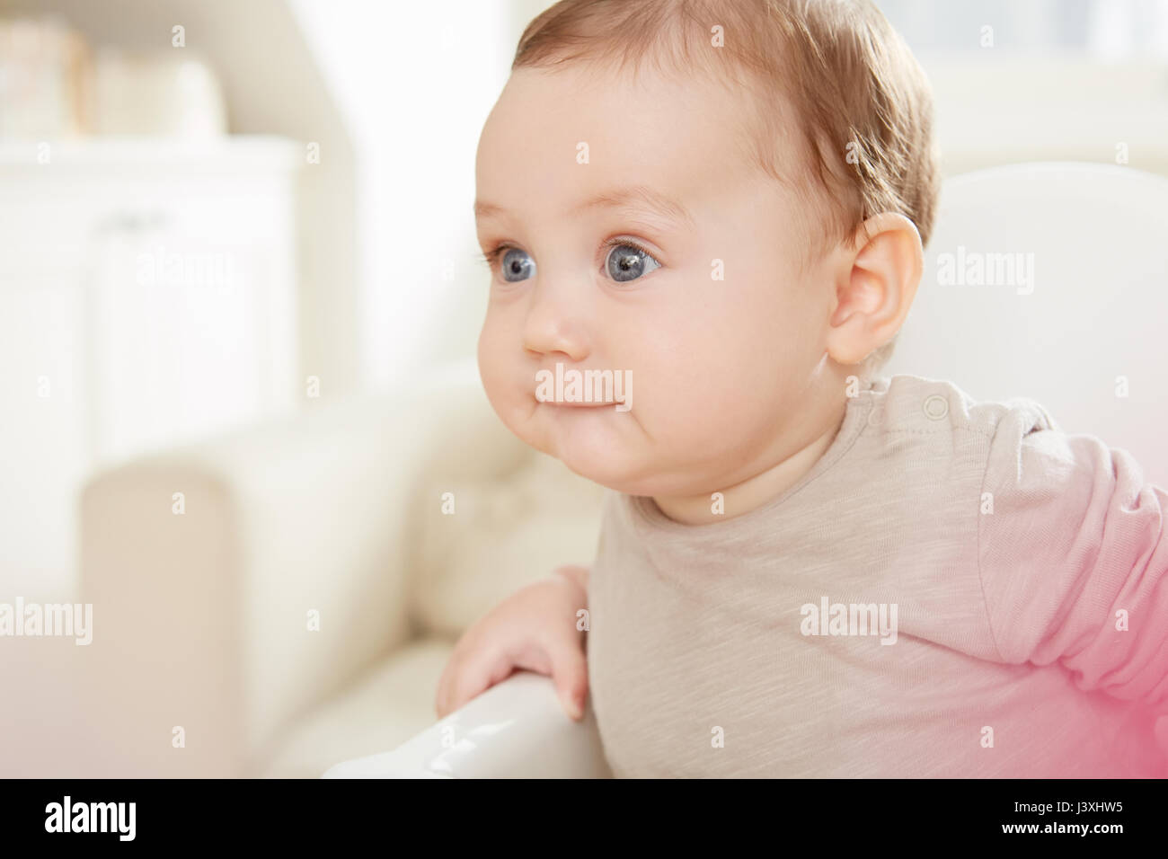 Blue Eyed baby boy fixant à partir de la chaise haute Banque D'Images