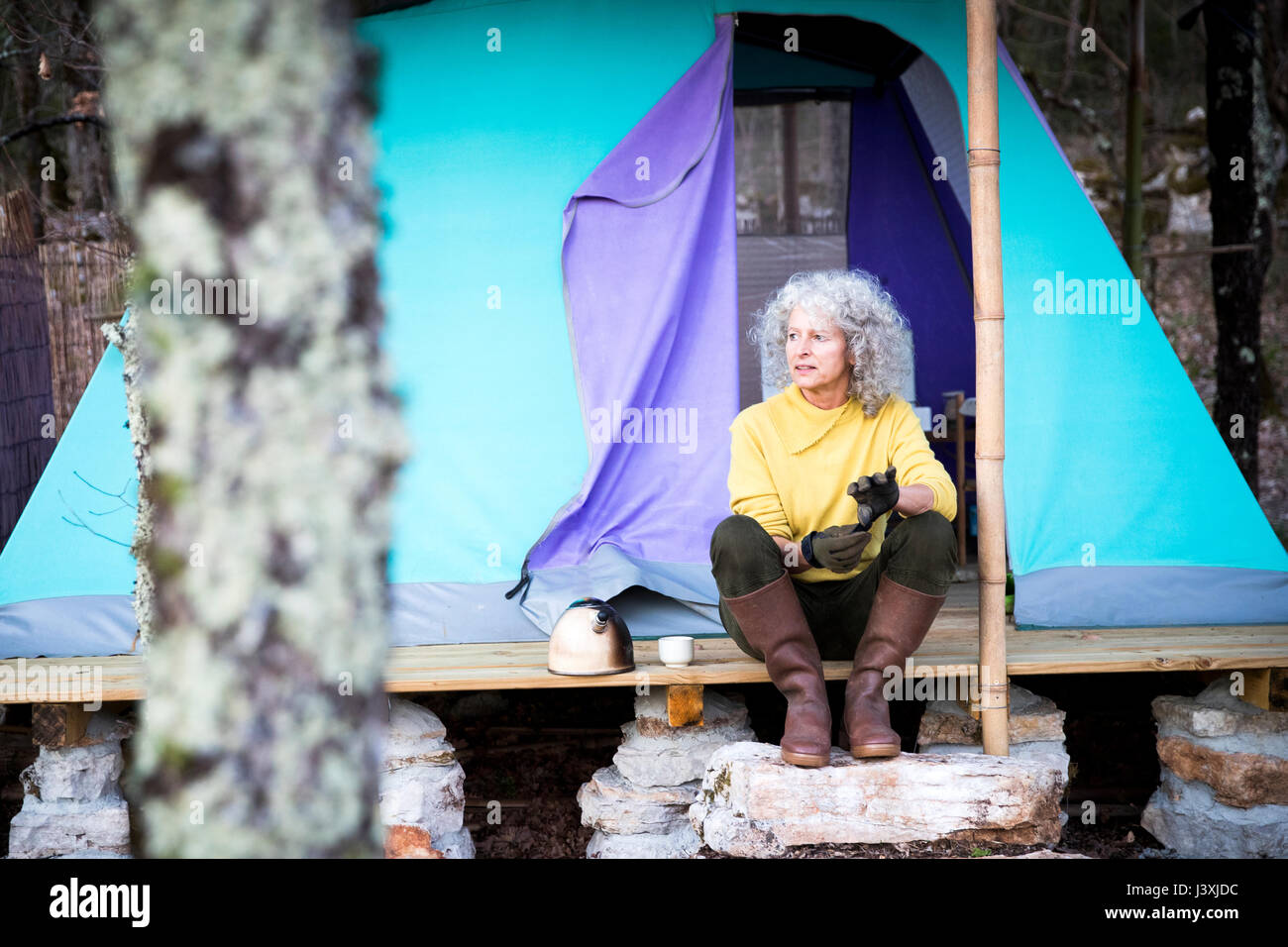 Mature Woman sitting on porche camping Woodland Banque D'Images