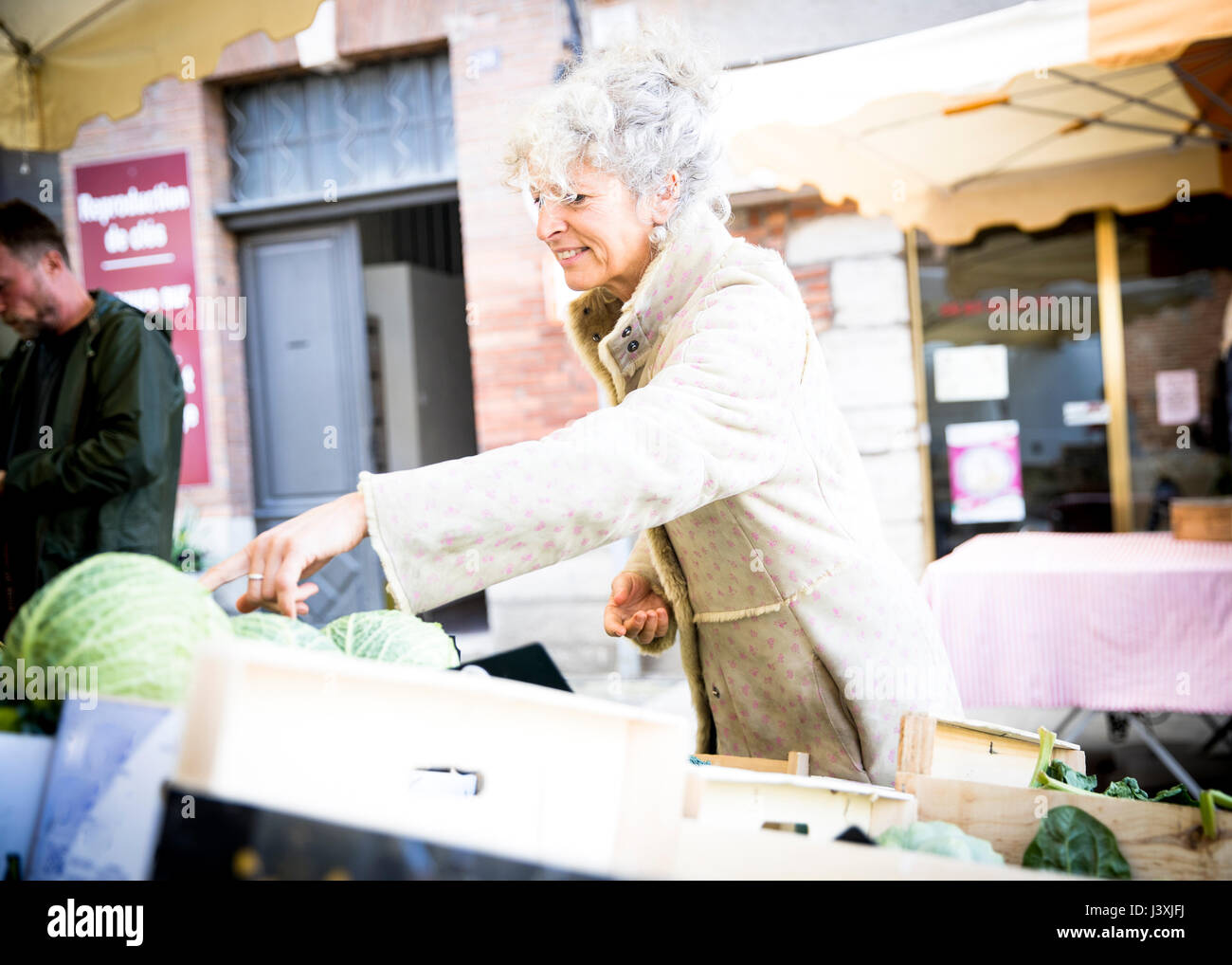 Femelle adulte nouveau client l'achat des légumes au marché français local Banque D'Images