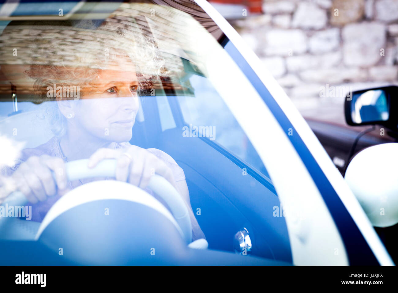 Smiling mature woman à la voiture par le biais de pare-brise Banque D'Images