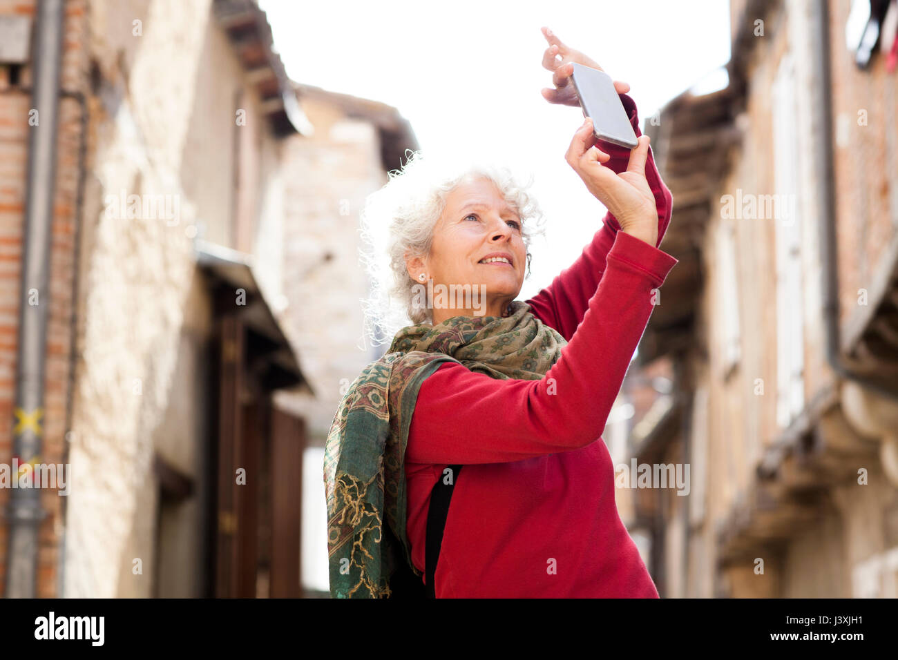 Woman taking photograph in street, Bruniquel, France Banque D'Images