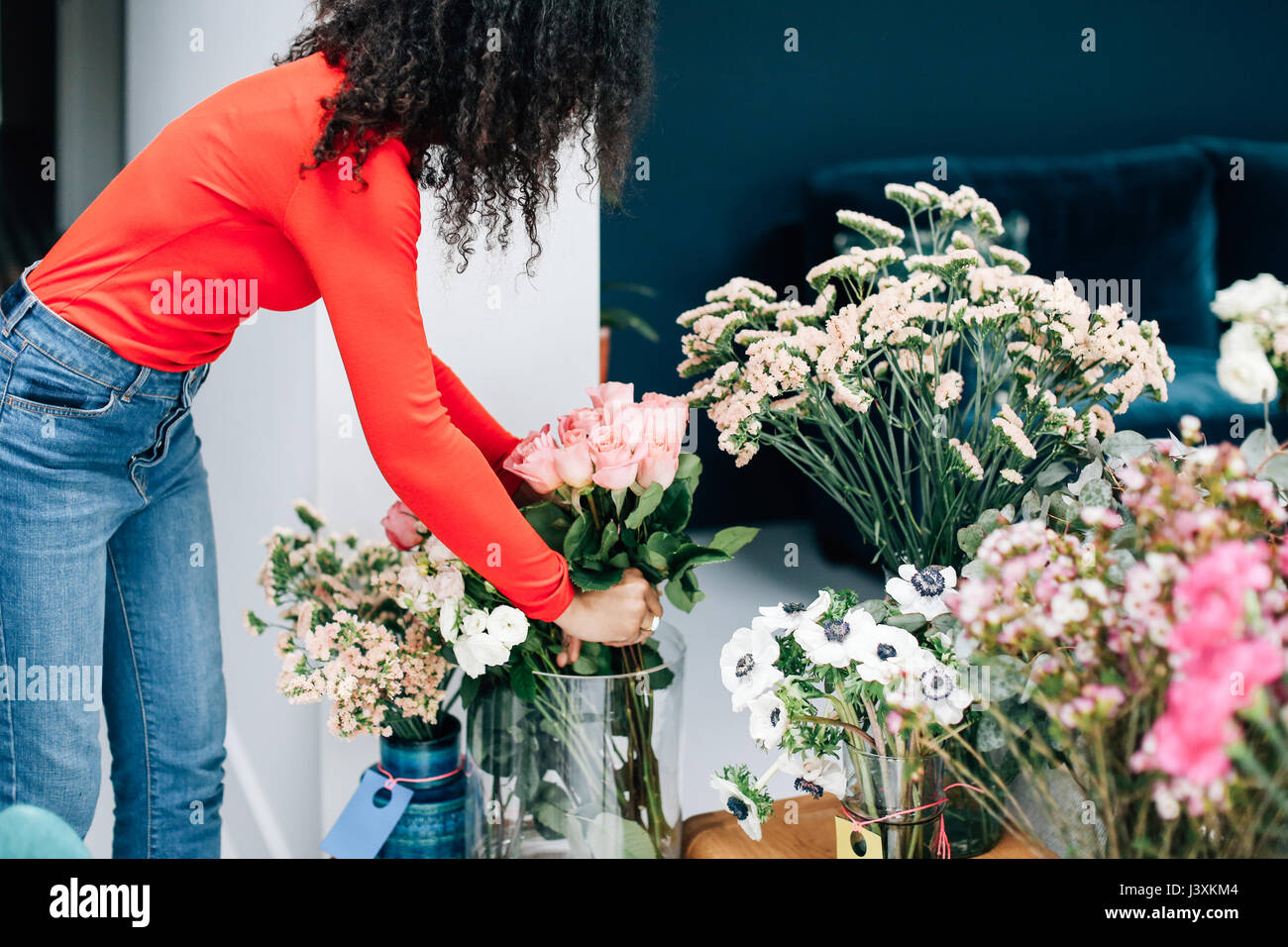 Female florist organiser roses pour la présentation en magasin Banque D'Images