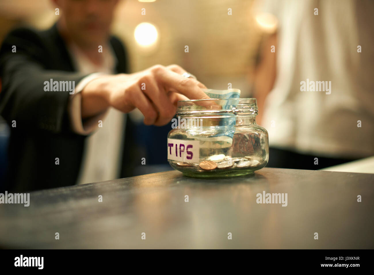 Close up of businessman mettant de l'argent en coiffure jar gratification Banque D'Images