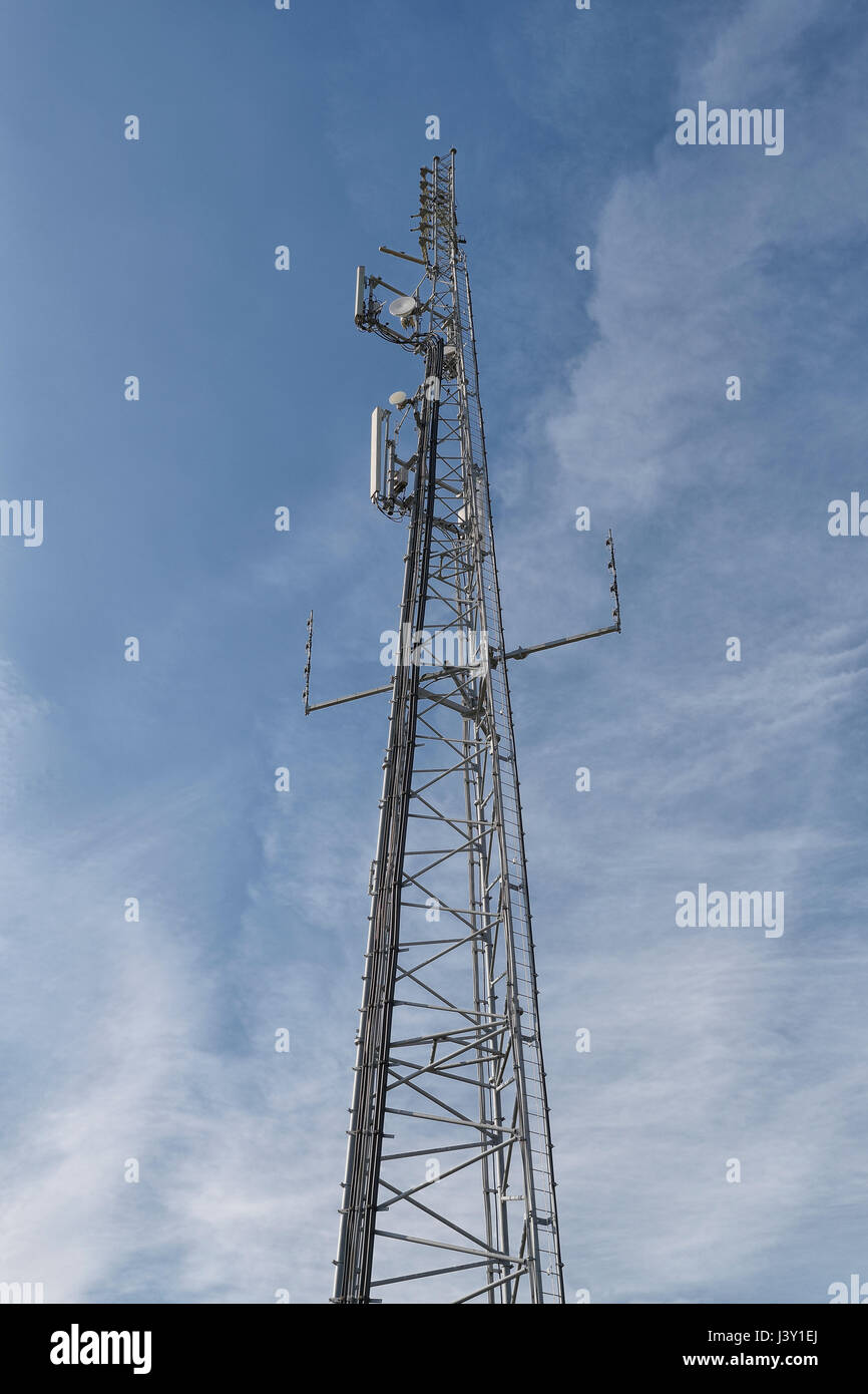 Mât de téléphonie mobile sur un ciel bleu avec des nuages filandreux. Banque D'Images