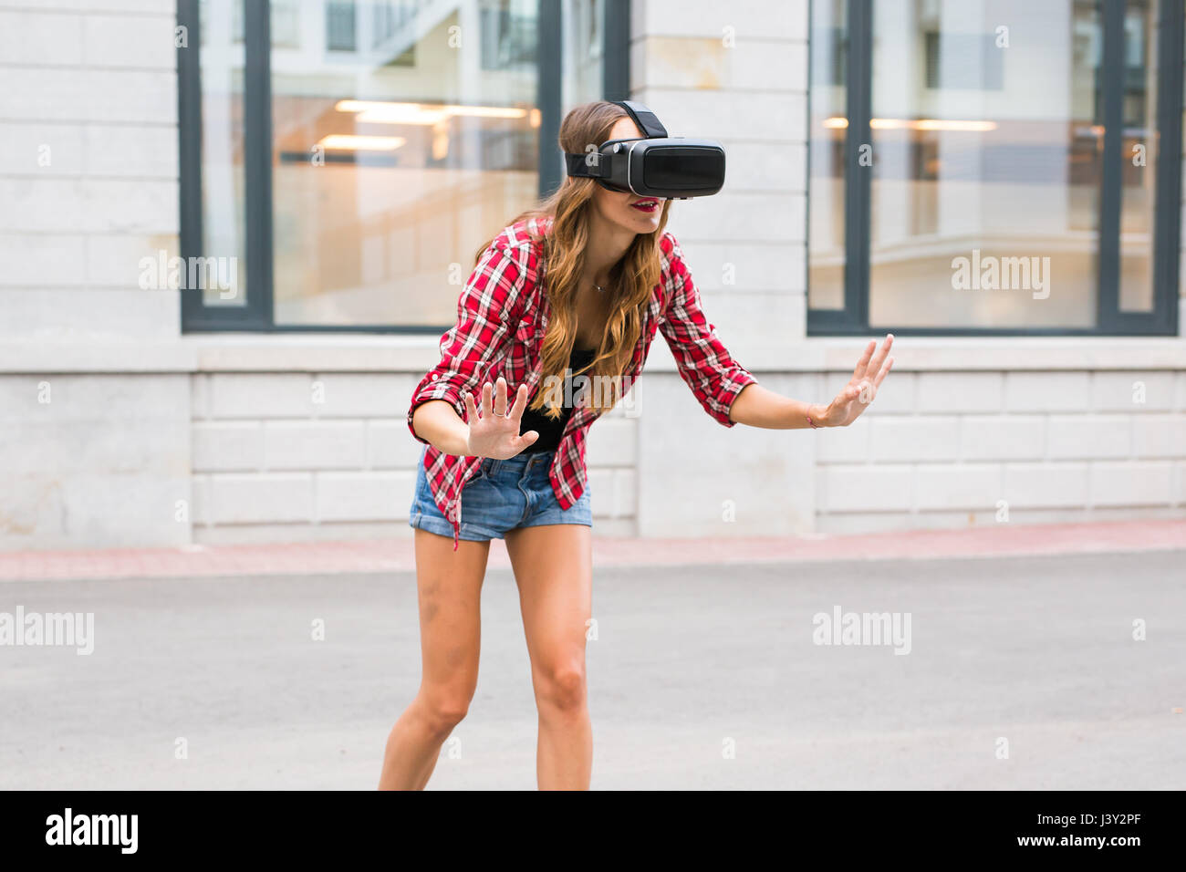 Belle jeune fille avec un casque de réalité virtuelle VR sur rue Banque D'Images