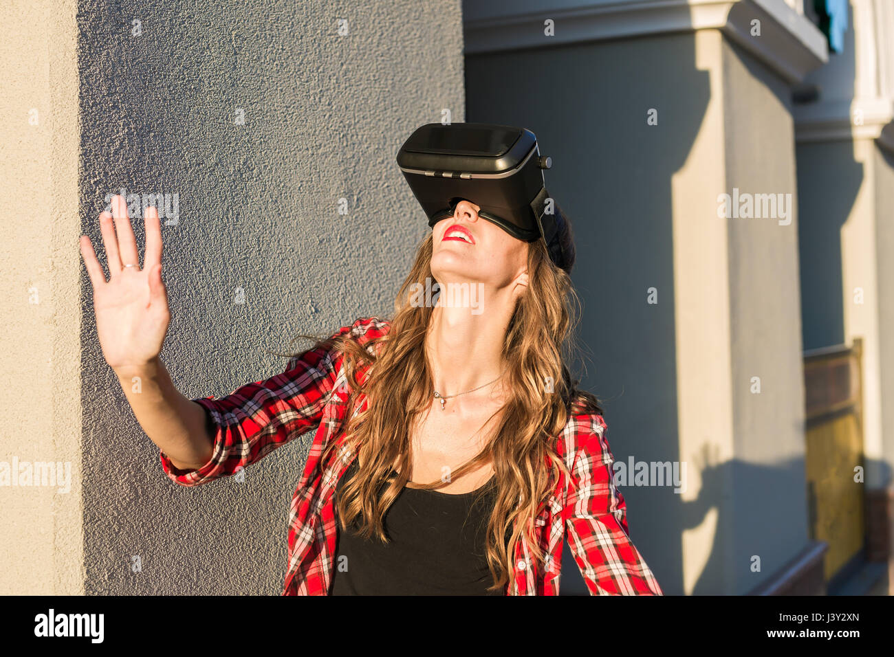 Belle jeune fille avec un casque de réalité virtuelle VR sur rue Banque D'Images