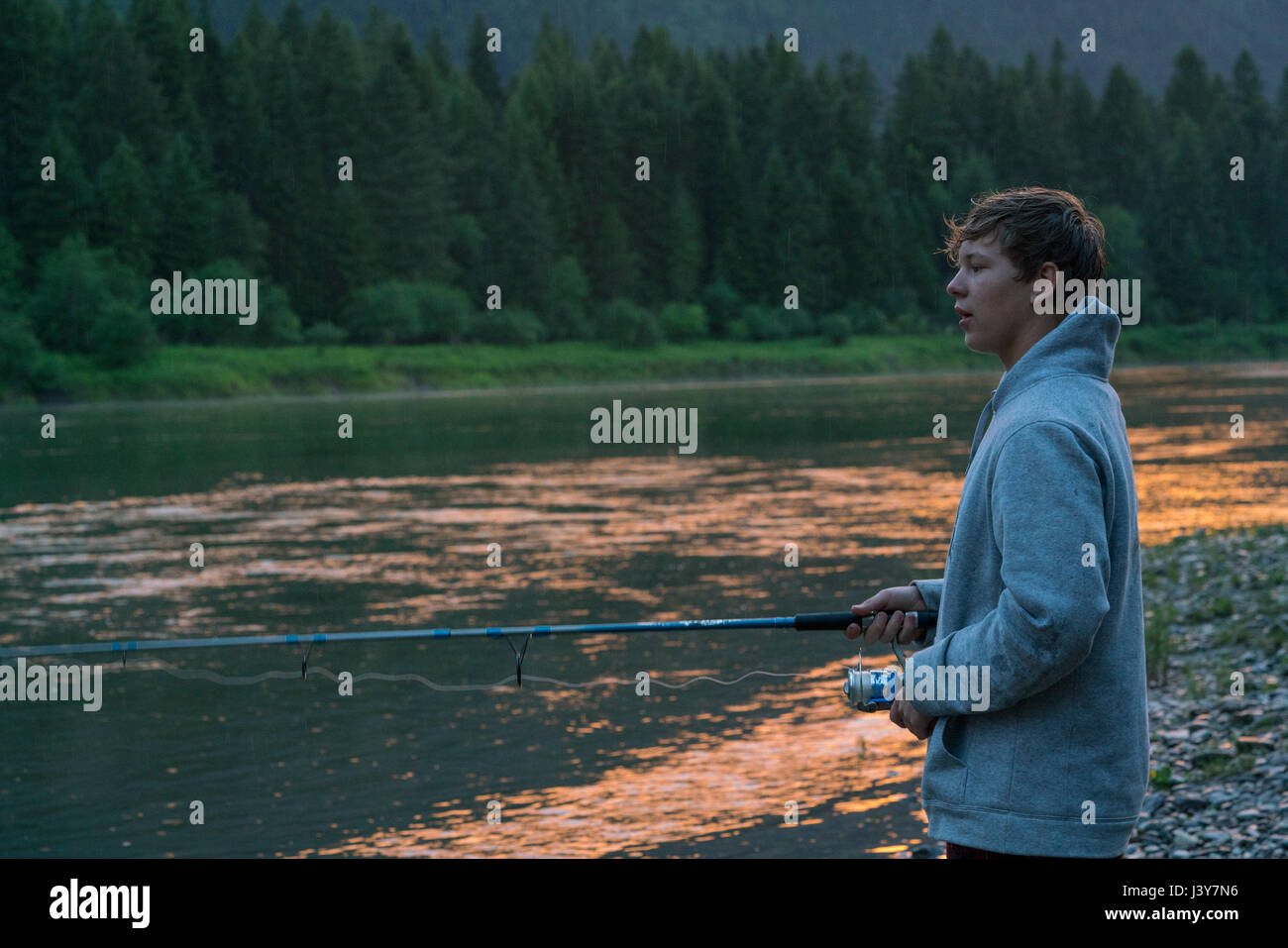 Teenage boy pêche en rivière au coucher du soleil, Washington, USA Banque D'Images