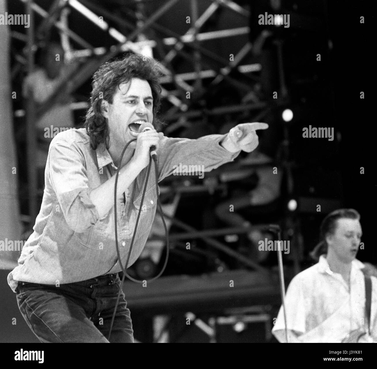 Bob Geldof, organisateur de la Live Aid concert, sur scène où il chante avec son groupe "The Boomtown Rats' au stade de Wembley, Londres. Banque D'Images