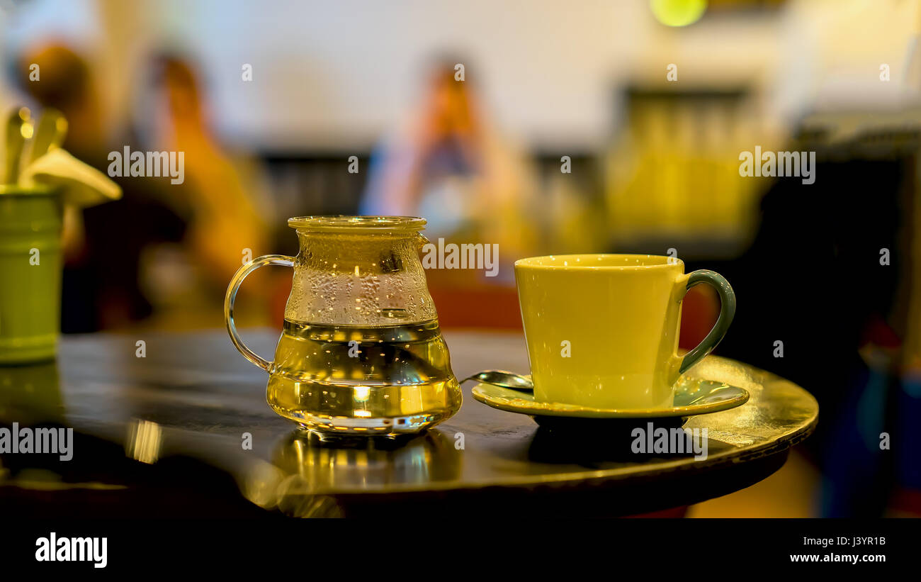 Tasse de café ou thé, théière en verre d'eau chaude, le matin. Image avec  les visiteurs dans un cafe floue clé faible, pour utiliser l'arrière-plan  Photo Stock - Alamy