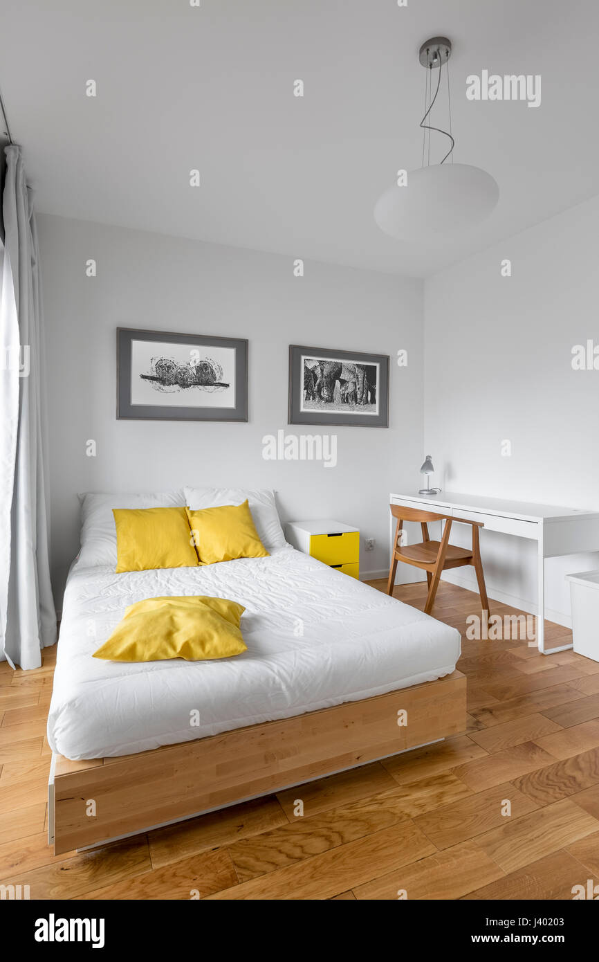 Blanc moderne chambre avec grand lit, un bureau en bois et décorations  jaune Photo Stock - Alamy