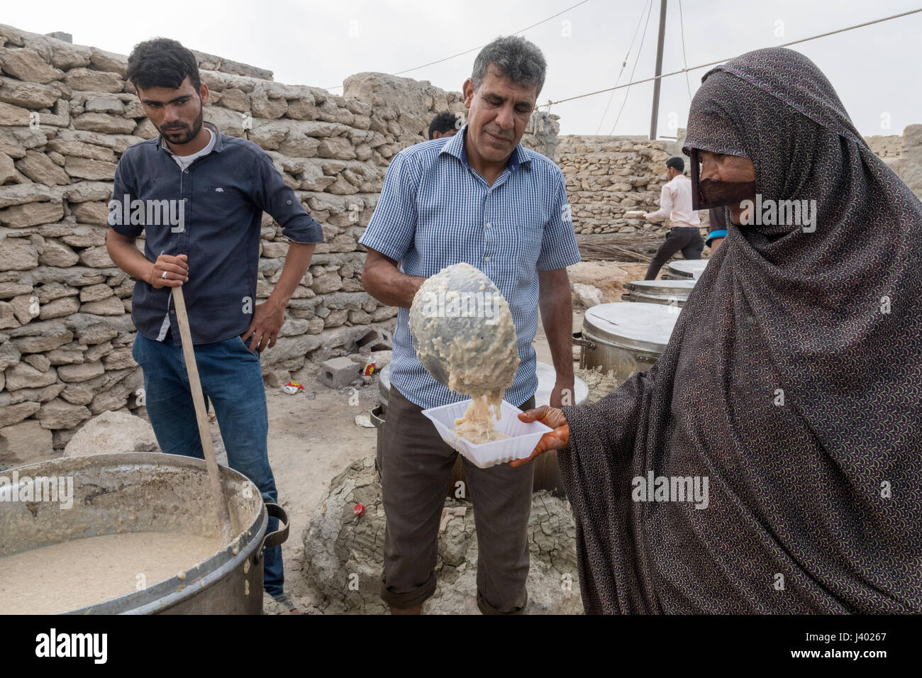 Hommes servant Halim -porridge local- à une dame dans un récipient en plastique, mariage traditionnel, l'île de Qeshm, Tabl, Province Hormozgan, IRAN Banque D'Images