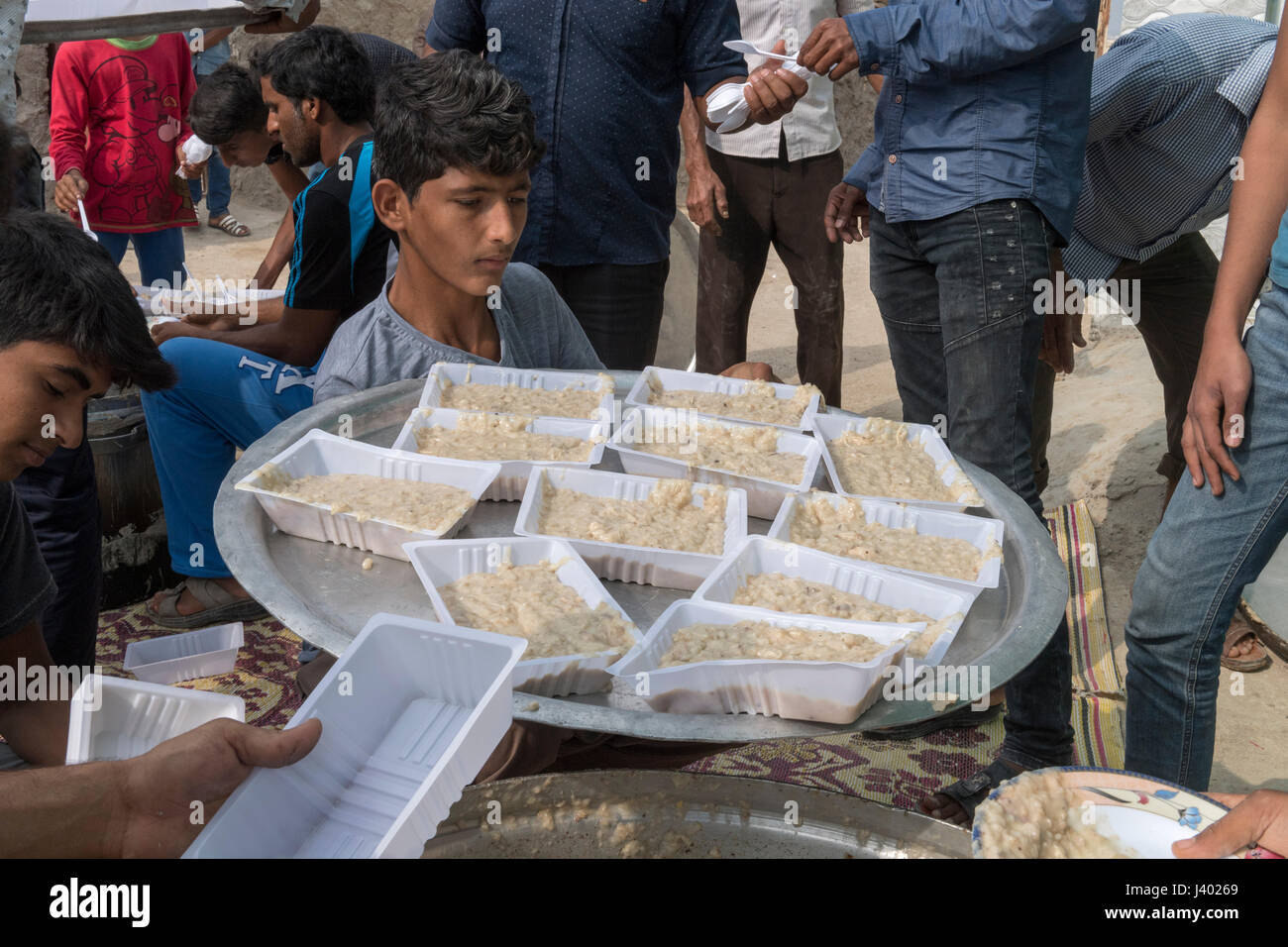 Hommes servant Halim -porridge local- dans des contenants en plastique pour être porté à vous, mariage traditionnel, l'île de Qeshm, Tabl, Province Hormozgan, IRAN - Banque D'Images