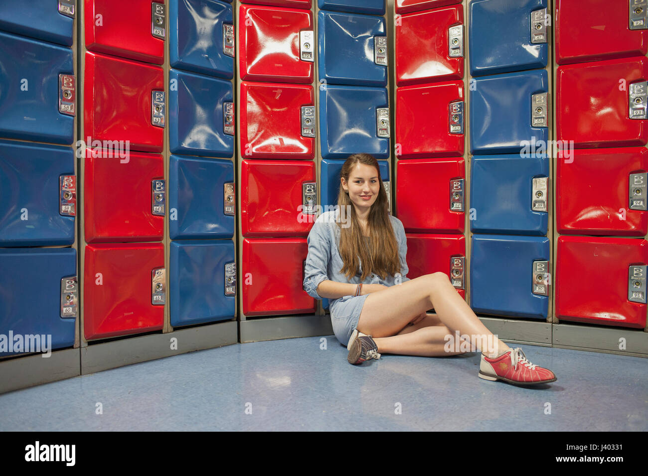 Une jeune femme par certains casiers rouge et bleu. Banque D'Images