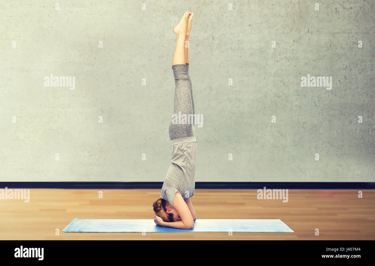 Femme faisant du yoga dans la tête poser sur mat Banque D'Images