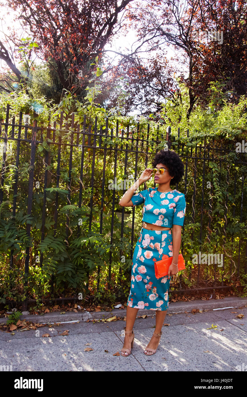 Jeune femme fashion blogger avec cheveux afro en attente sur trottoir Park, New York, USA Banque D'Images