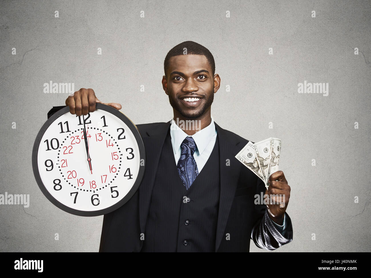 Closeup portrait jeune homme d'affaires, du personnel de l'entreprise, chef de la direction, holding horloge murale, billets d'un dollar dans les mains. Time is money concept, isolé, noir Banque D'Images