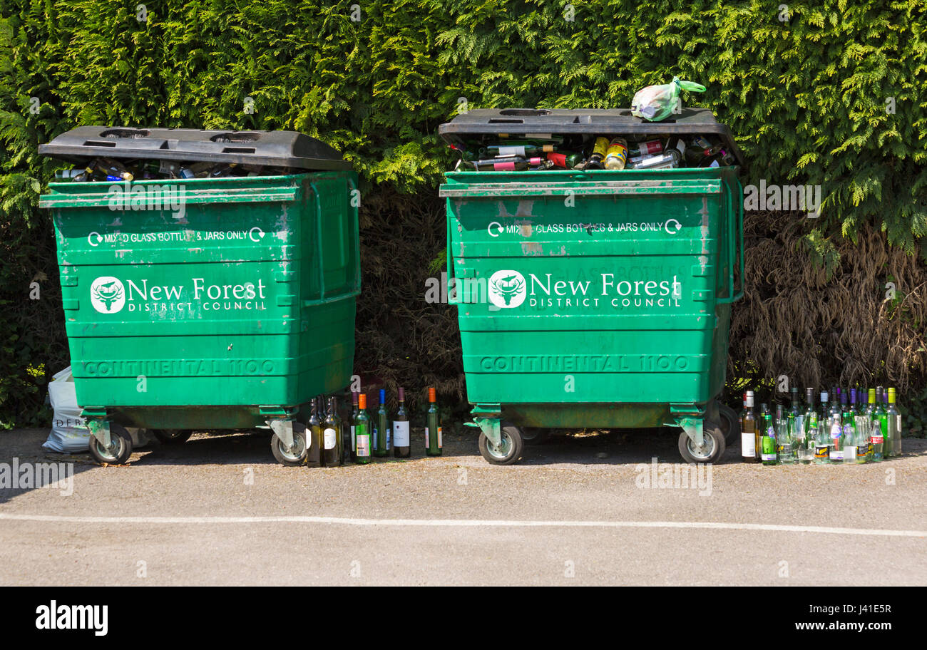 Les bacs de recyclage pour les bouteilles en verre et les bocaux uniquement par le conseil de district de New Forest - bacs débordante avec des bouteilles sur le terrain par le côté Banque D'Images