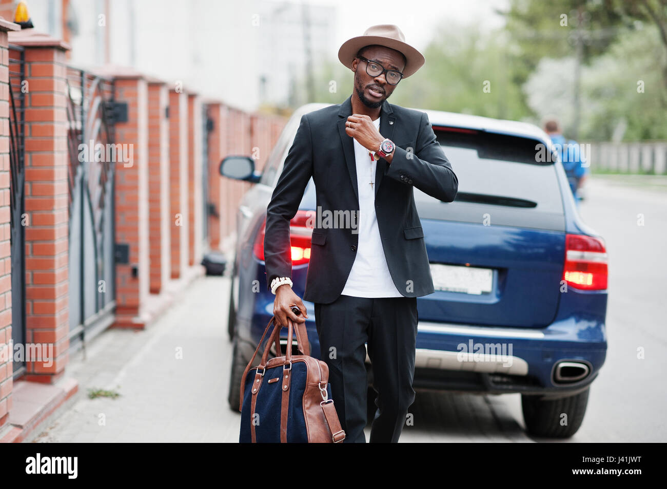 L'homme noir élégant avec chapeau, lunettes à l'usure de costume avec sac à  main contre la voiture de luxe. African American businessman riche Photo  Stock - Alamy