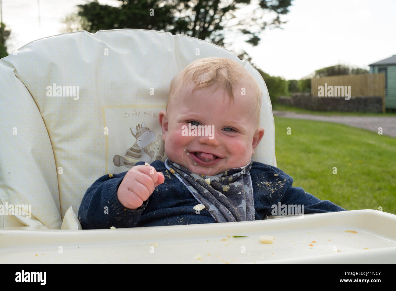 Bébé de sept mois sous chaise haute, Hope Cove, Devon, Angleterre, Royaume-Uni. Banque D'Images