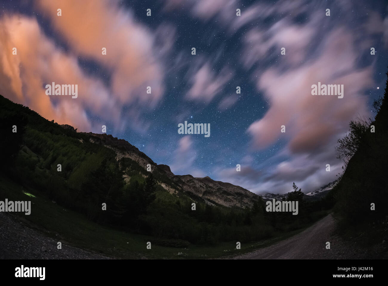 Le ciel étoilé avec les nuages colorés commuters et clair de lune. Vaste paysage de nuit dans les Alpes européennes, ultra large fisheye view. Banque D'Images