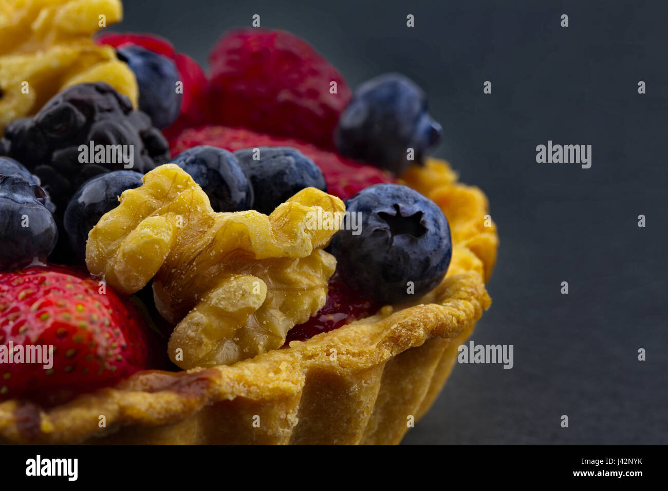 Tarte aux noix Fruits et baies, y compris les fraises, framboises, mûres, et les bleuets en macro photographie avec fond noir. Banque D'Images