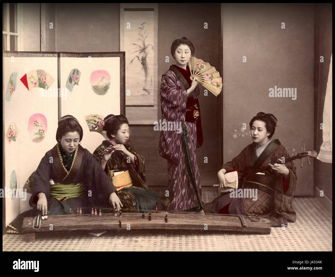 Cette photographie de Kusakabe Kimbei montre quatre femmes engagées dans la musique, représentant probablement la culture japonaise traditionnelle. L'image est une représentation historique des coutumes et de l'art japonais. Banque D'Images