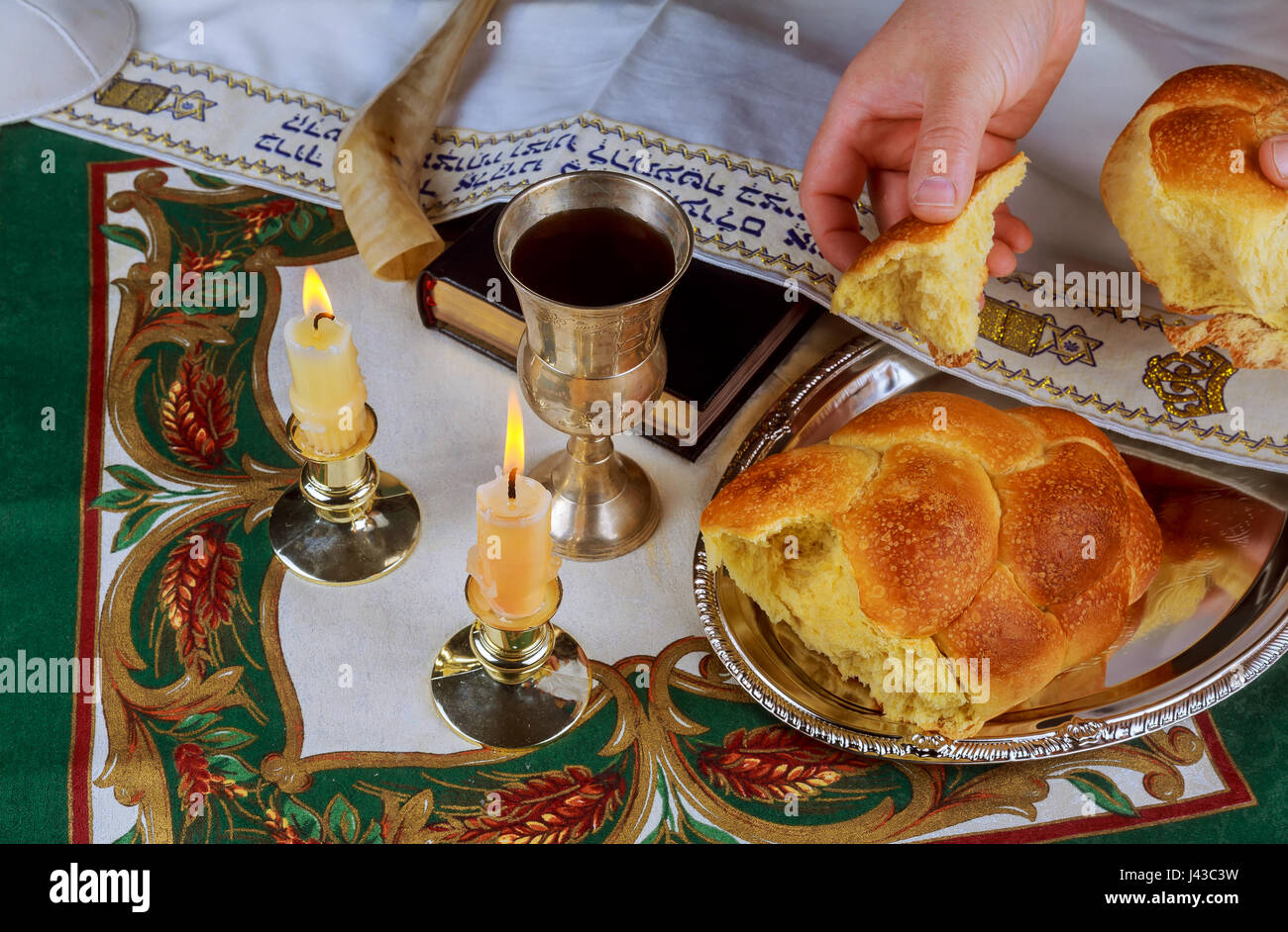Les bougies du Chabbat dans les chandeliers de verre je fond flou de pain challah couverts en argent plateau sur nappe blanche. Banque D'Images