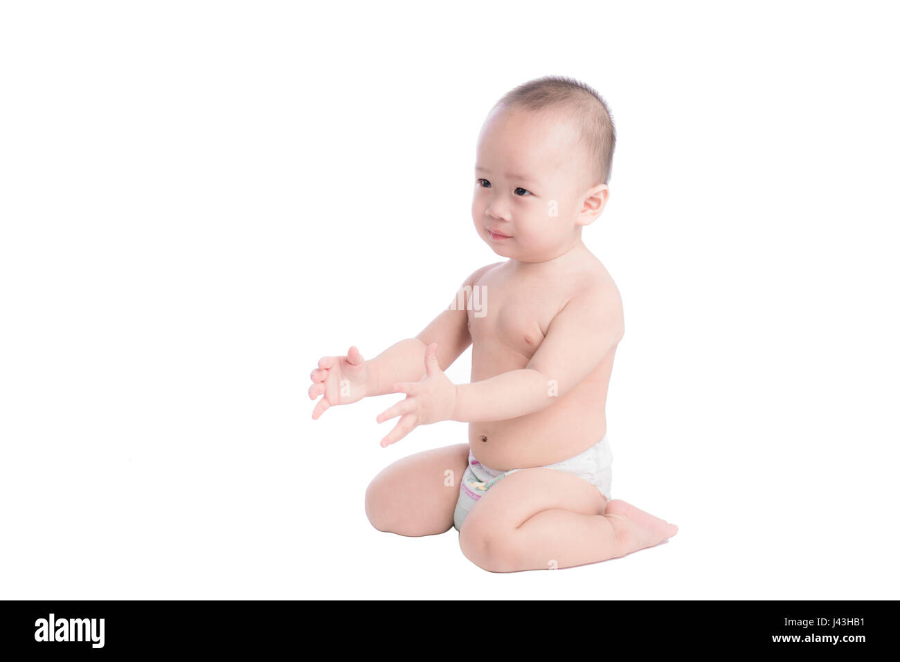 Portrait of a cute smiling little boy sitting on floor, isolé sur fond blanc Banque D'Images