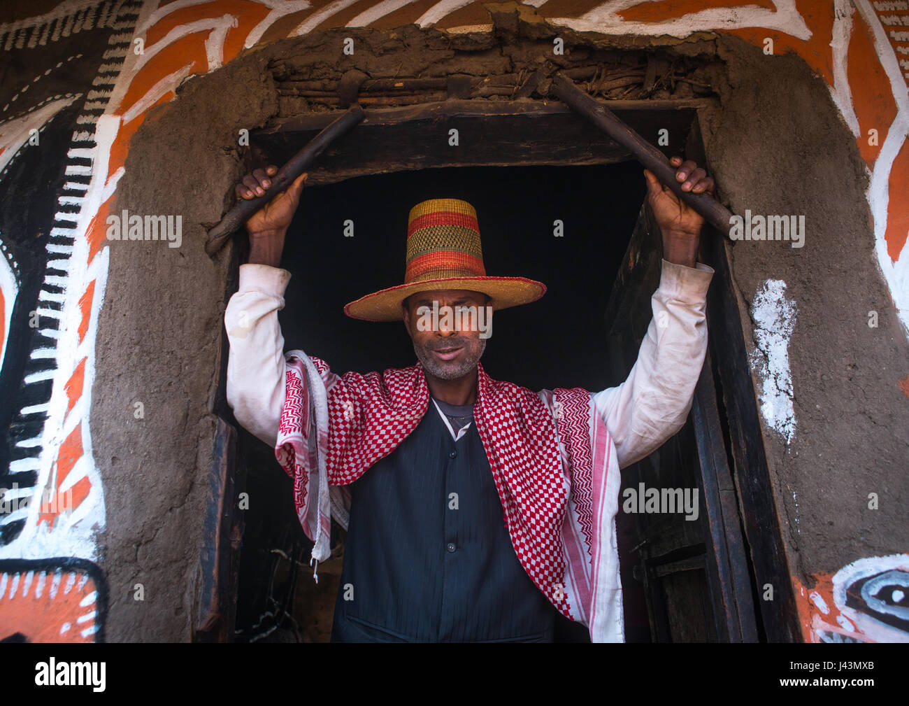 L'homme musulman éthiopien avec un chapeau debout devant sa maison, peint traditionnel Kembata Alaba, Kuito, Ethiopie Banque D'Images