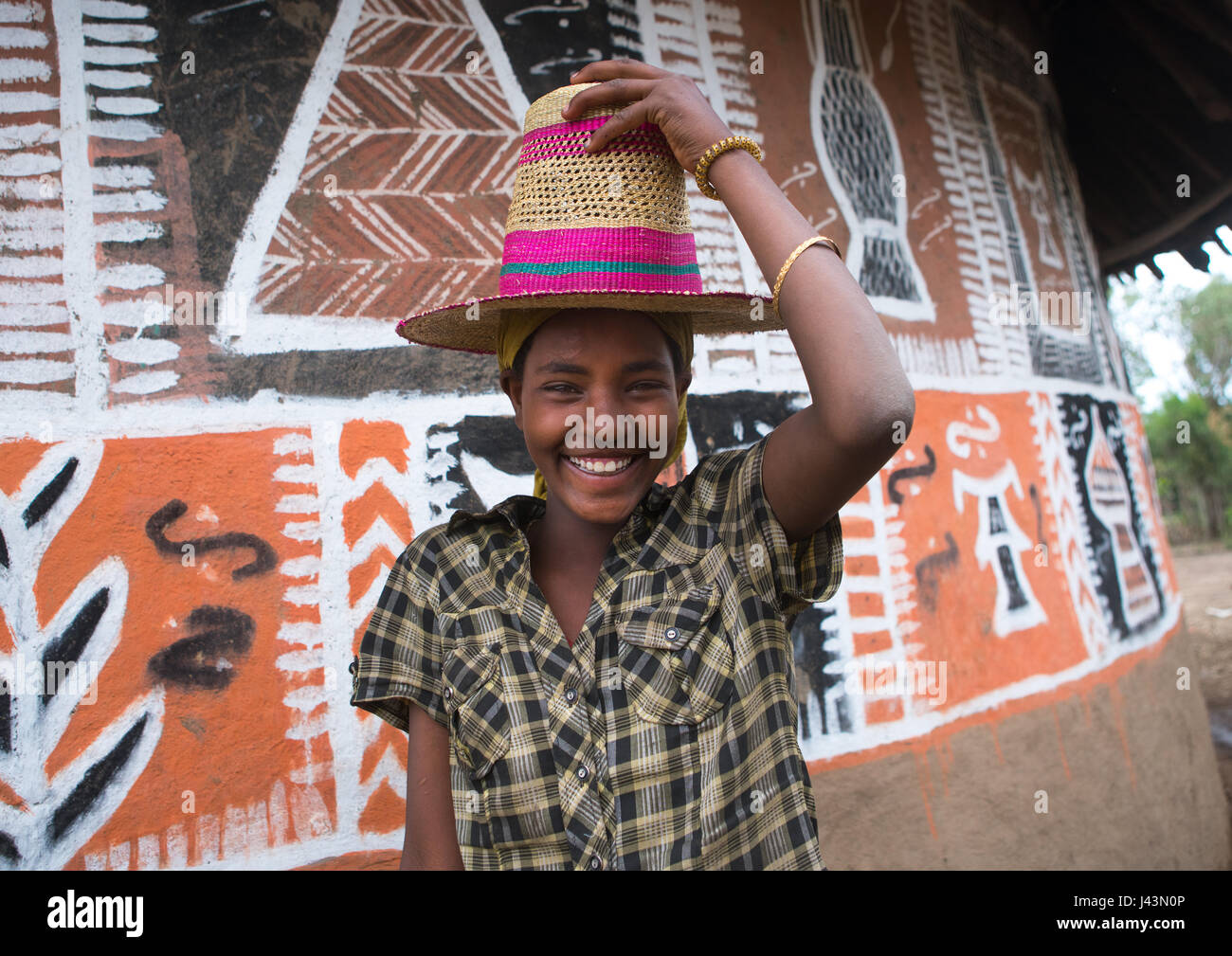 Femme éthiopienne avec un chapeau debout devant sa maison, peint traditionnel Kembata Alaba, Kuito, Ethiopie Banque D'Images