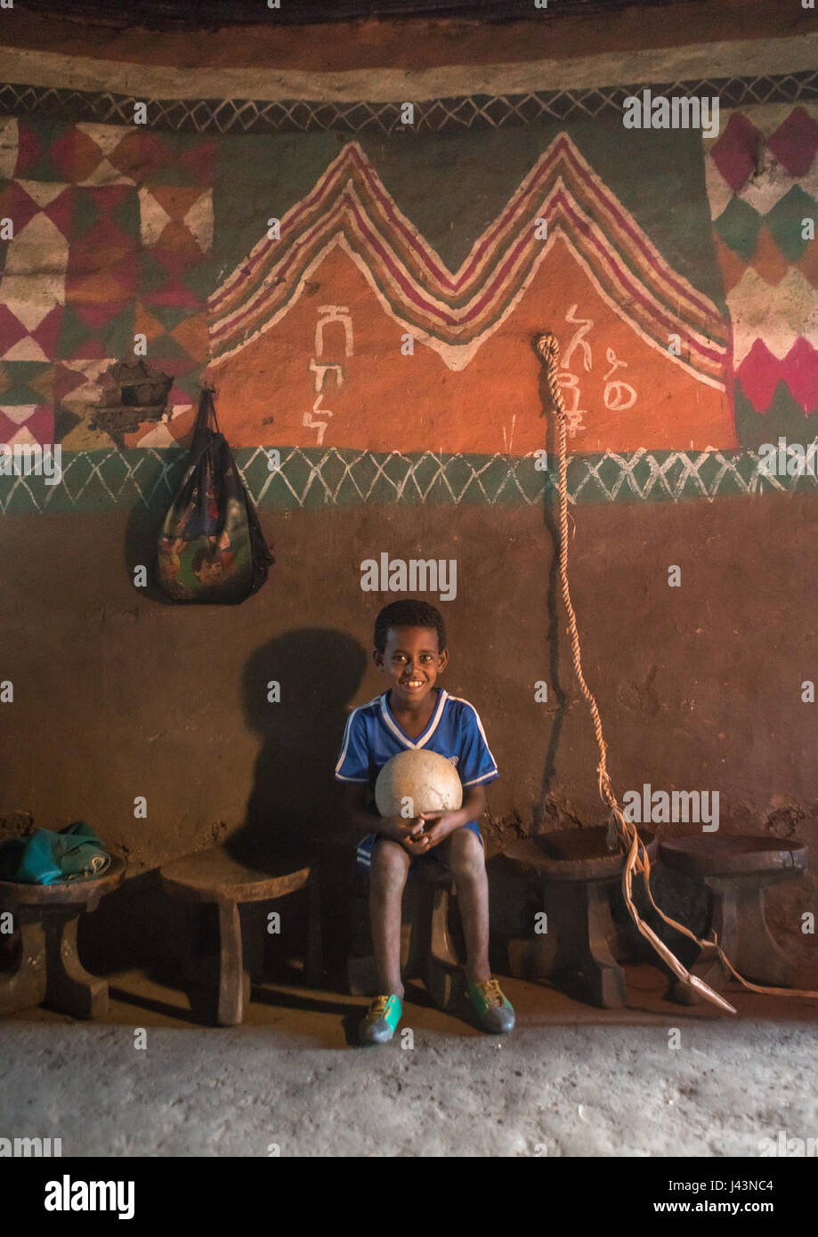 Garçon éthiopien à l'intérieur de son traditionnel peint et décoré maison, Kembata Alaba, Kuito, Ethiopie Banque D'Images