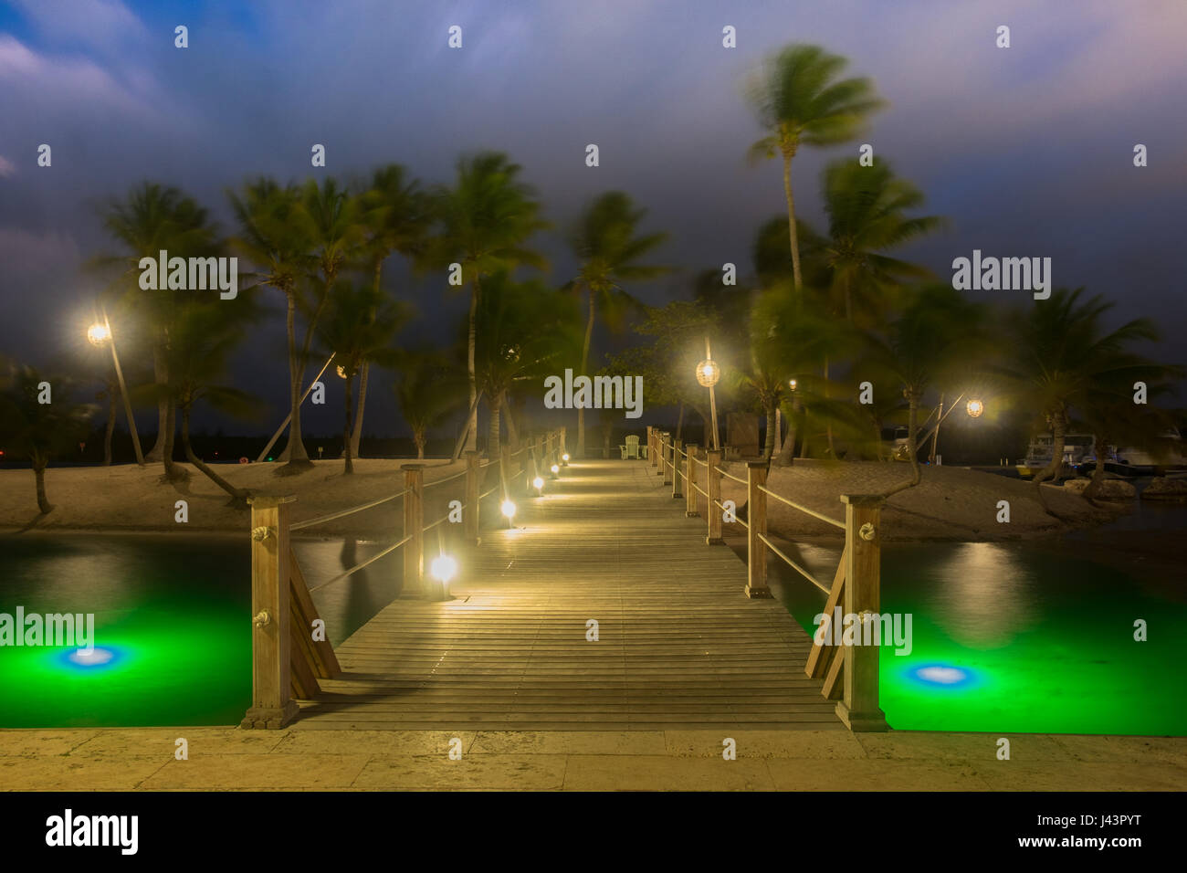 Pont en bois à Camana Bay, s'étend sur la mer des Caraïbes de l'île menant à lanternes illuminées par une nuit de grand vent, sur Grand Cayman, Cayman Islands Banque D'Images