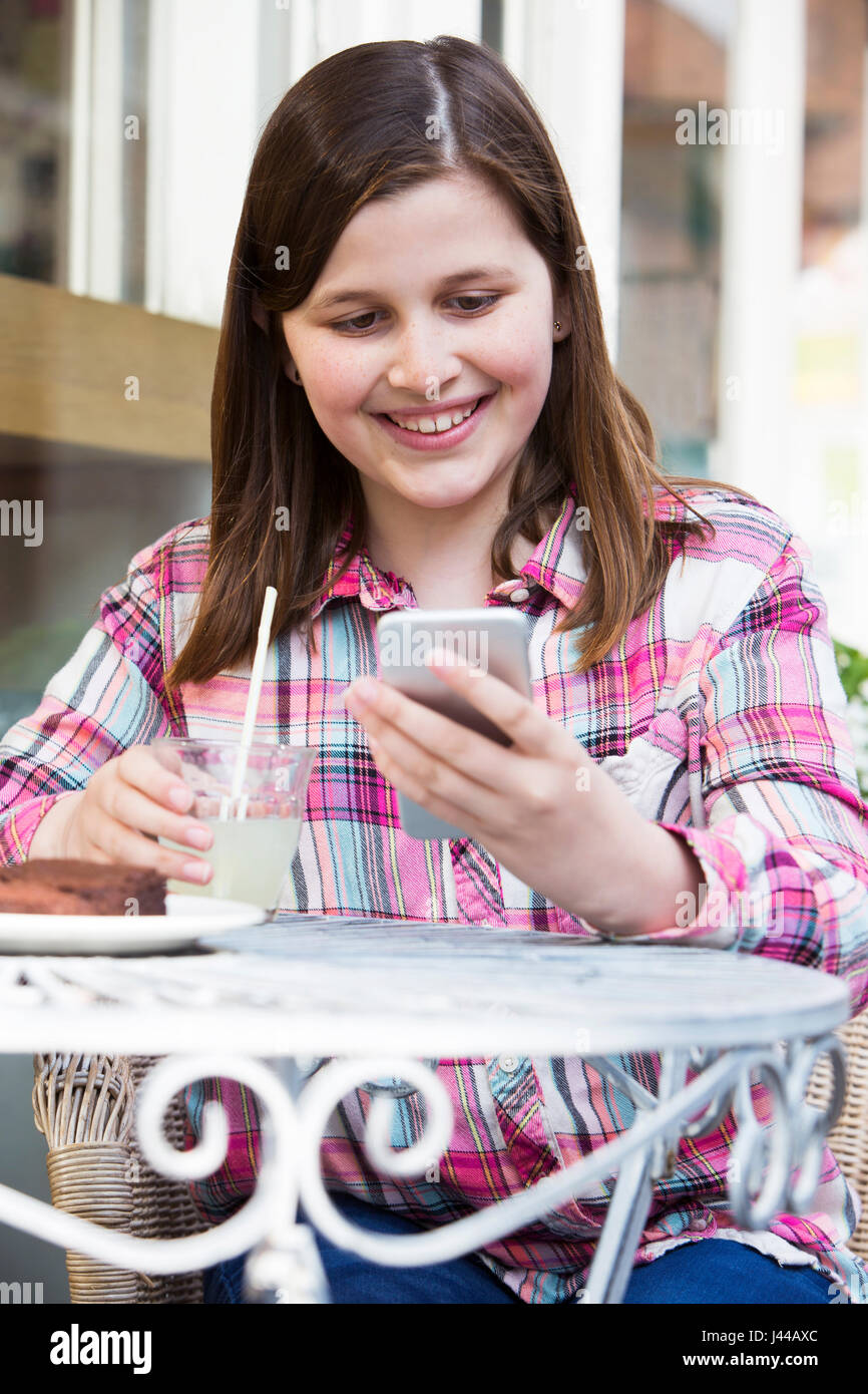 Jeune fille au Café Lecture Text Message On Mobile Phone Banque D'Images