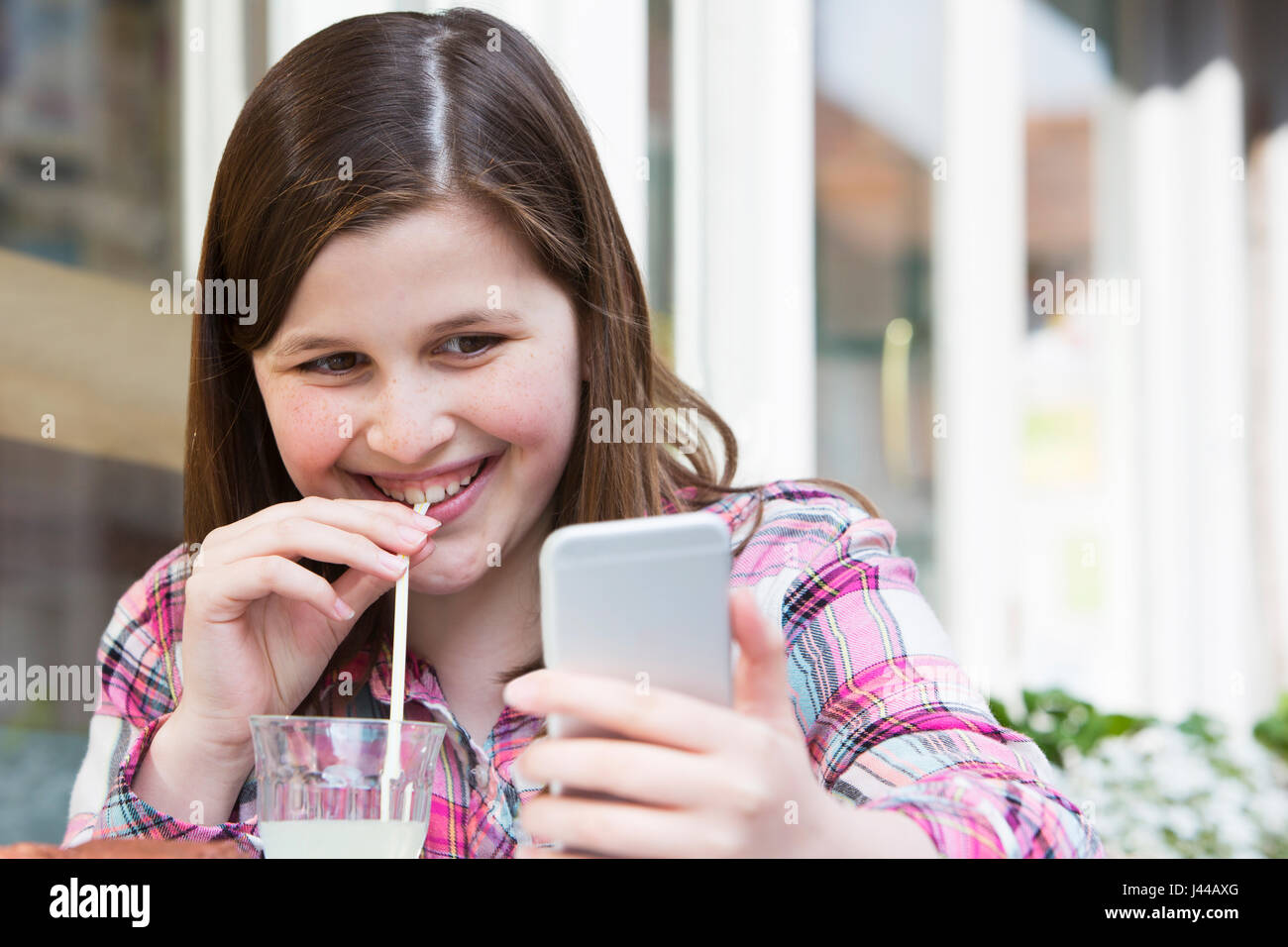 Jeune fille au Café Lecture Text Message On Mobile Phone Banque D'Images