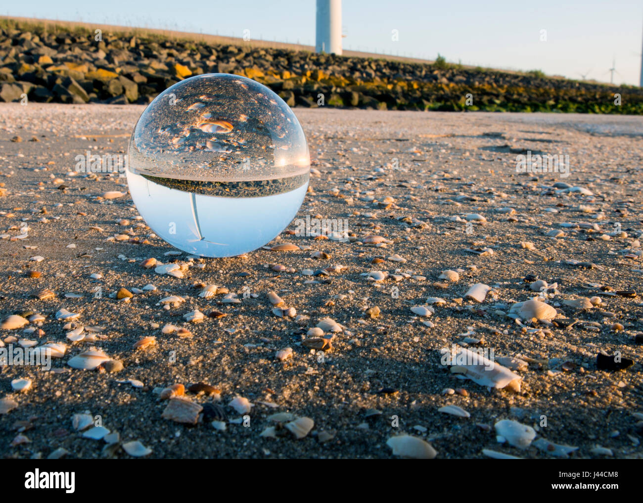 Spehere de cristal avec reflet d'aérogénérateurs et de shell sur la plage près de Windmill Park Banque D'Images