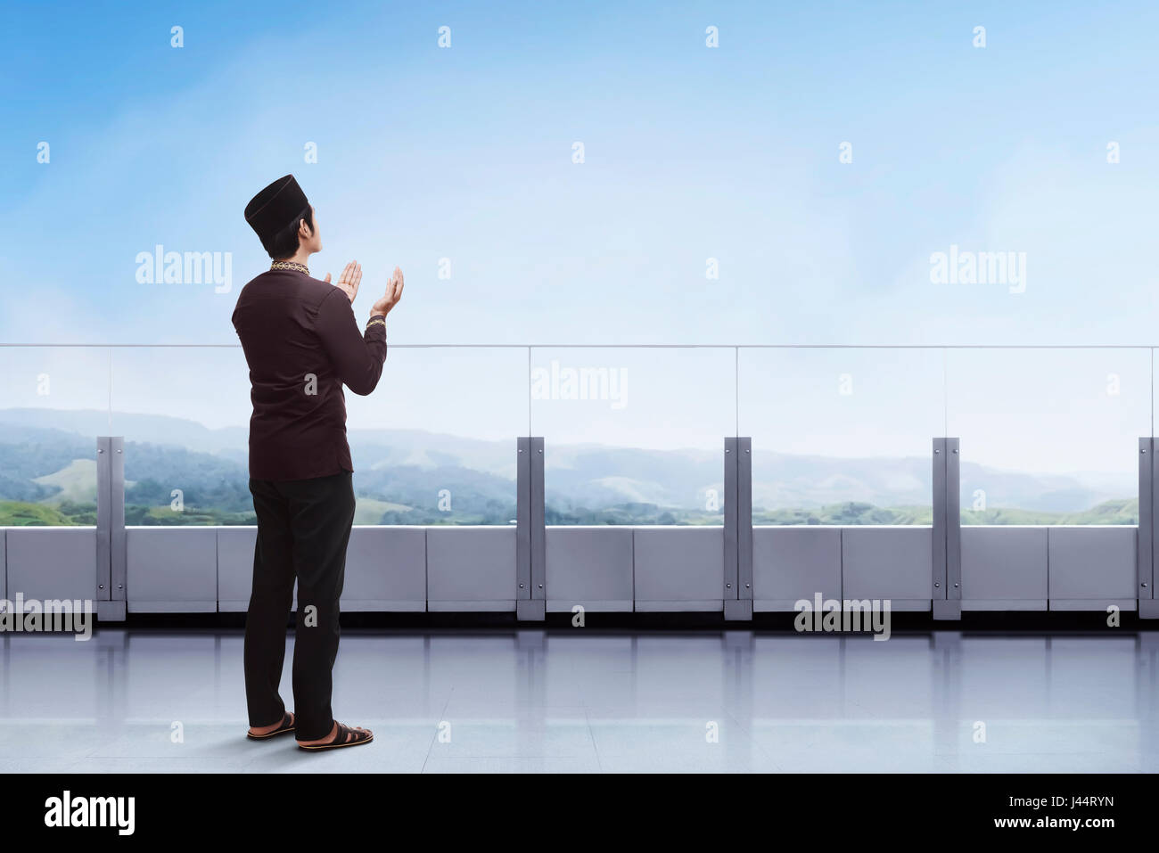 Les jeunes musulmans asiatiques homme priant avec la main dans le balcon avec vue paysage historique Banque D'Images